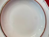a white plate with a gold rim on a red table