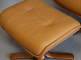 a brown leather chair and ottoman on the floor