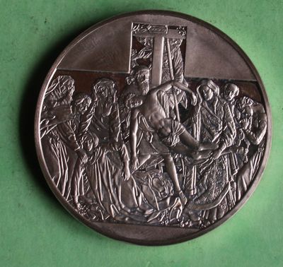 an antique silver medal depicting a man on a cross surrounded by soldiers