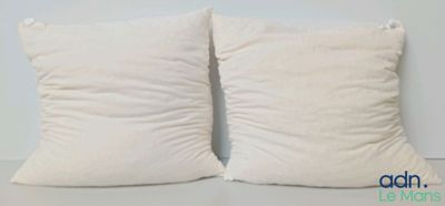 deux oreillers blancs posés sur une table blanche près d'un mur