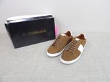 des baskets marron à semelles blanches, avec une boîte posée sur une surface blanche