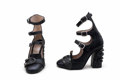 une paire de chaussures noires à talons hauts, ornées de boucles de chaque côté