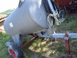 a cement mixer sitting on a trailer in the grass