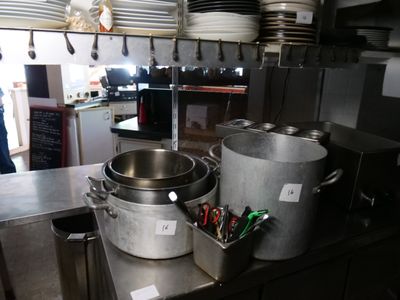 des casseroles et des poêles sont posées sur un plan de travail dans une cuisine professionnelle