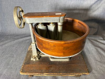 une vieille machine en bois et en métal, surmontée d'un bol en bois