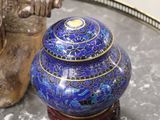 a blue vase sitting on a table next to a gold figurine