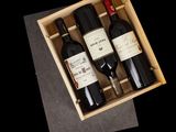 three bottles of wine in a wooden box on a table
