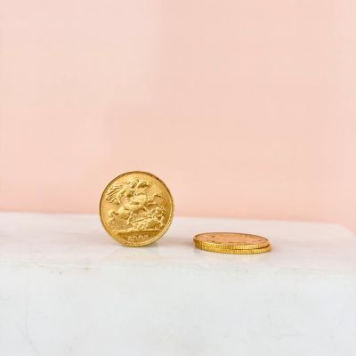 a gold coin sitting on top of a white table next to a pink wall