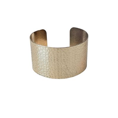 a close up of a gold cuff bracelet on a white background