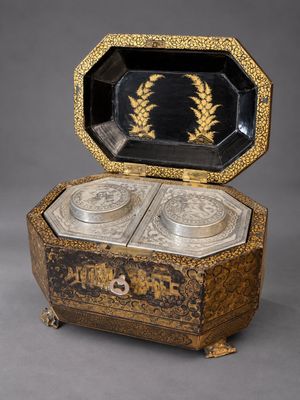 une boîte noire et dorée contenant deux plats en argent