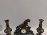 trois vases et une horloge posés sur une table