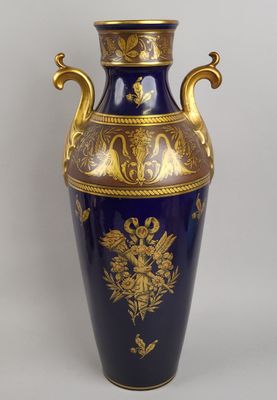 un vase bleu orné de motifs dorés sur fond blanc
