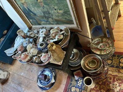 une pile d'assiettes et de bols posée par terre à côté d'un tableau