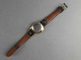 wrist watch with brown leather strap on a gray surface