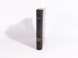 un vieux livre noir posé sur une surface blanche