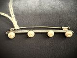 a close up of a brooch with pearls on it