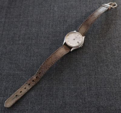 un gros plan d'une montre-bracelet posée sur une surface grise