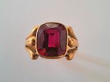 gros plan d'une bague en or avec une pierre rouge