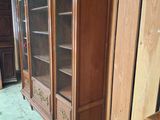 a wooden cabinet with a glass door and a guitar on the floor