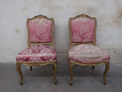 pair of pink and gold chairs against a white wall in a room