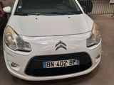 La voiture blanche est garée dans le garage, à côté d'autres voitures.