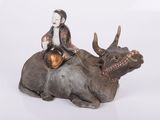 une figurine représentant un homme assis sur une vache