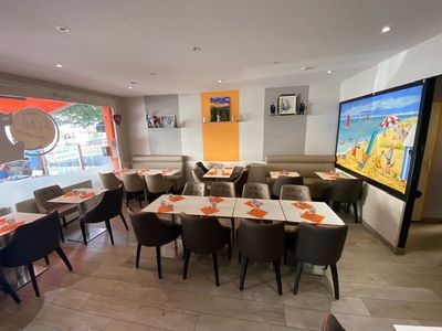 tables and chairs in a restaurant with a large screen on the wall