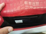 a person holding a red purse with a tag on it