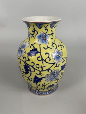 un vase jaune orné de fleurs bleues et blanches