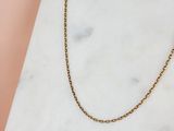 un collier à chaîne en or posé sur une surface en marbre