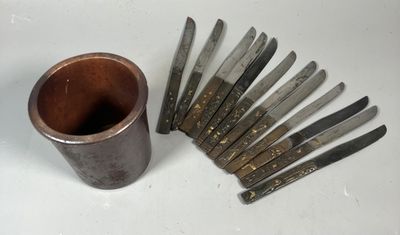 un tas de couteaux posés à côté d'une tasse