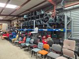 de nombreuses chaises, empilées dans un entrepôt
