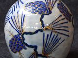 a blue and white vase with pinecones on it