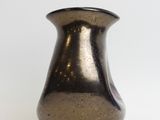 a small metallic vase sitting on a white surface