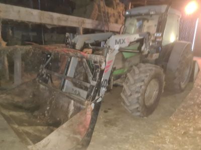 un tracteur garé sur la terre battue près d'une clôture