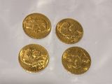four gold coins sitting on top of a white surface