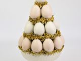 un petit sapin de Noël fait d'œufs, posé sur un socle blanc