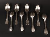six silver spoons are lined up in a row on a black surface
