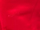 the back of a woman ' s red dress with a small embroidered star on it