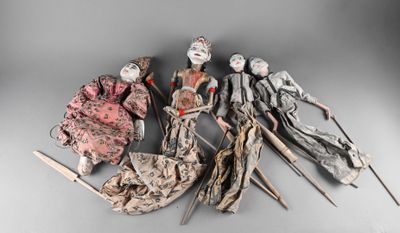 five antique dolls are lined up in a row on a gray surface