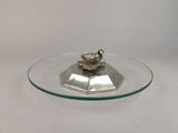 une plaque de verre sur laquelle est posé un oiseau en argent