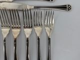 six forks and a knife on a table