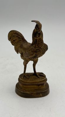 statue of a rooster on a wooden base on a white surface