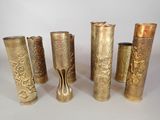 six brass vases are lined up in a row on a white surface