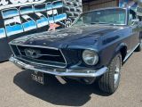 une Mustang bleue garée devant un immeuble