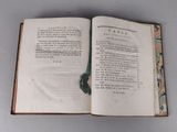 an open book on a table with a green ribbon on it