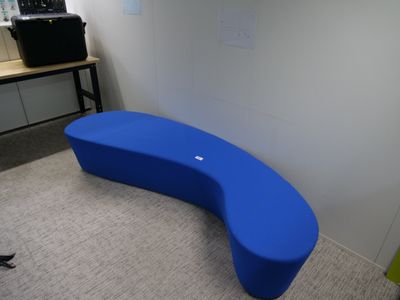 un banc bleu incurvé dans un coin de la pièce