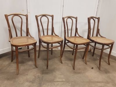 Quatre chaises en bois sont alignées contre un mur dans une pièce