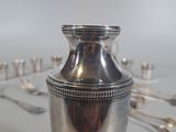 a silver vase sitting on a table with spoons in the background