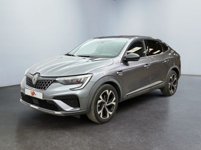 Une voiture grise est garée dans une pièce au sol noir.